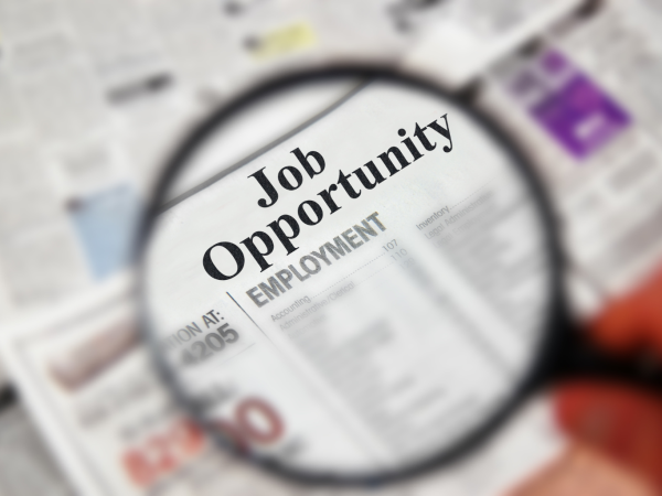 Magnifying glass showing the text 'job opportunity' on a newspaper